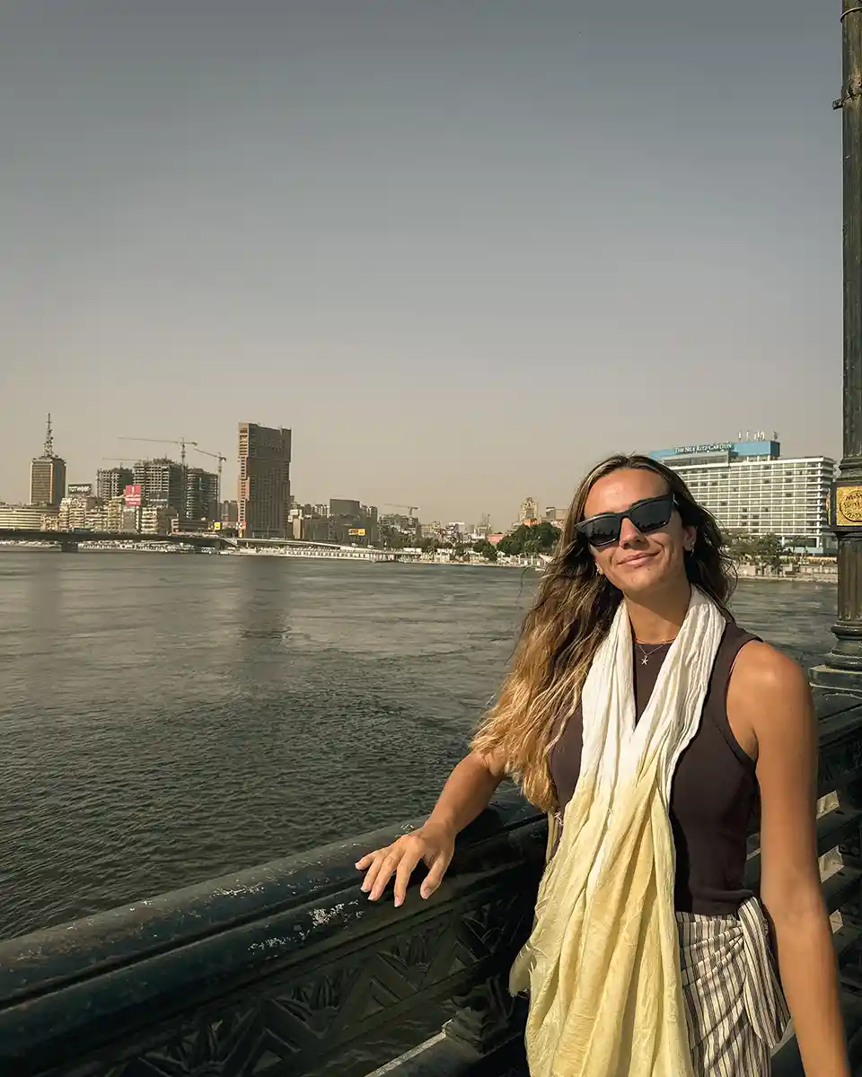 about-me-cairo Lucy smiling at the camera on Kasr Al Nile Bridge bridge with the Nile River and downtown Cairo in the background.