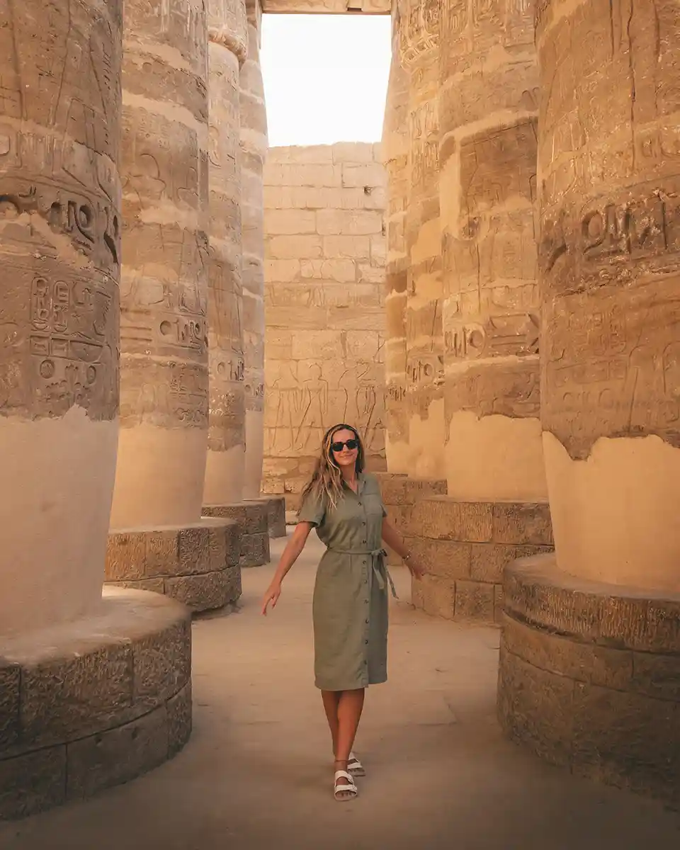 about-me-luxor Lucy standing between two rows of large columns in Karnak Temple.