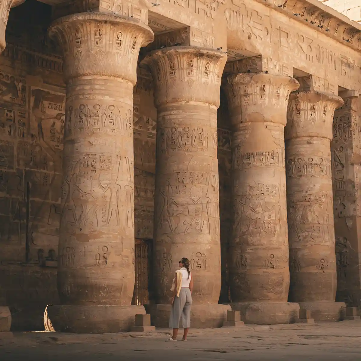 lucy-habu-medinat-home Lucy standing in front of four large pillars which are inscribed with Ancient Egyptian hieroglyphs.