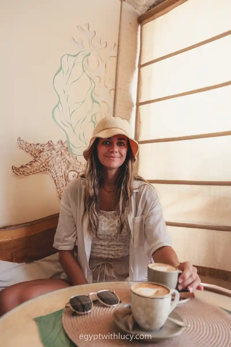 Lucy sits behind two lattes at a table inside Avenue Cafe.