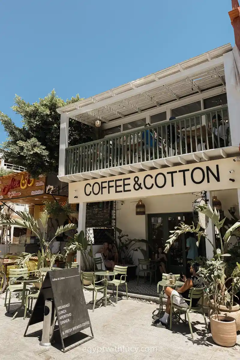 Customers sit at outdoor tables in front of the Coffee & Cotton storefront.
