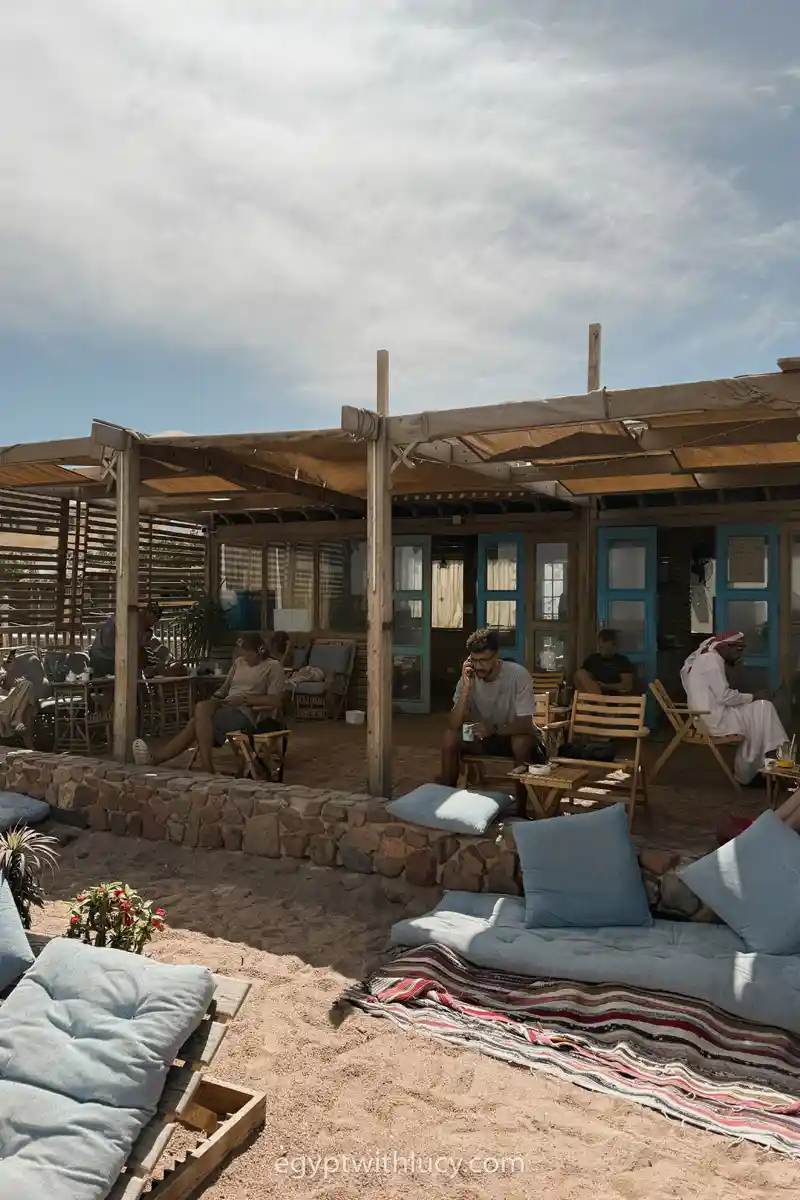 People sit under a canopy on the sand at Coffee Wheel.