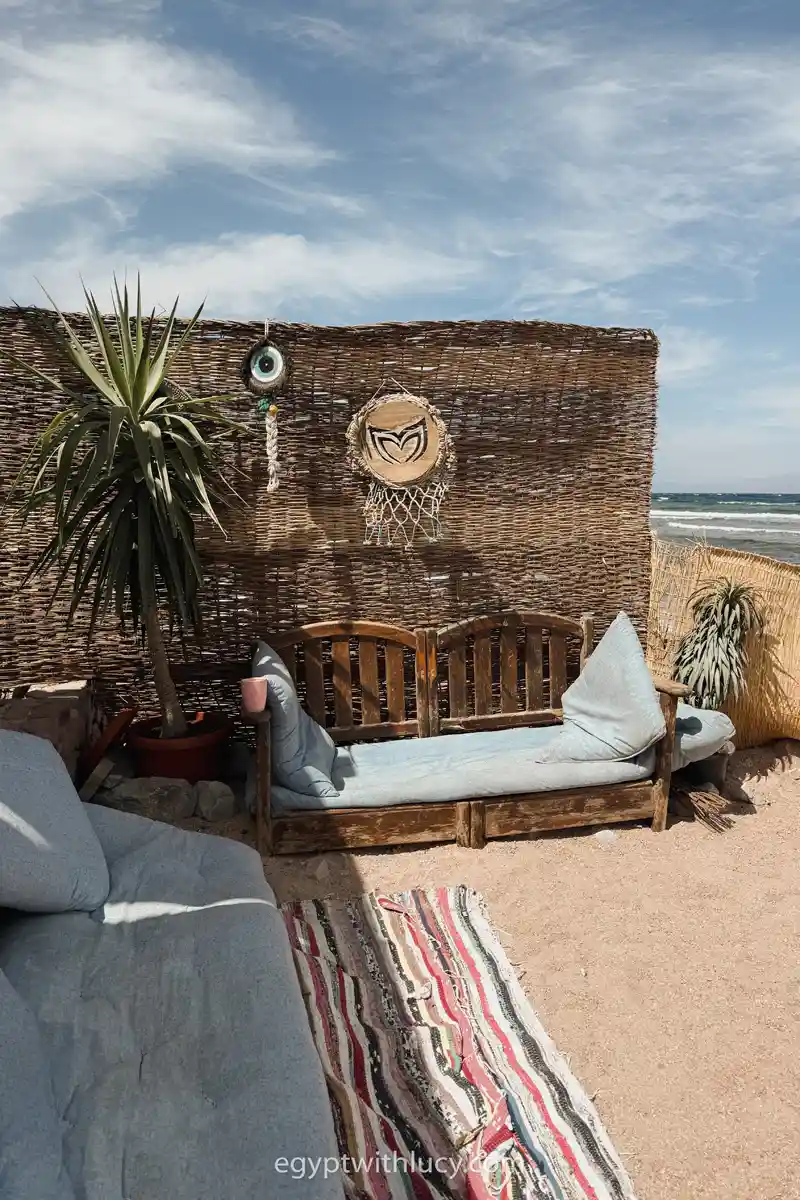 A bench stands on the sand next to a wall at Coffee Wheel.