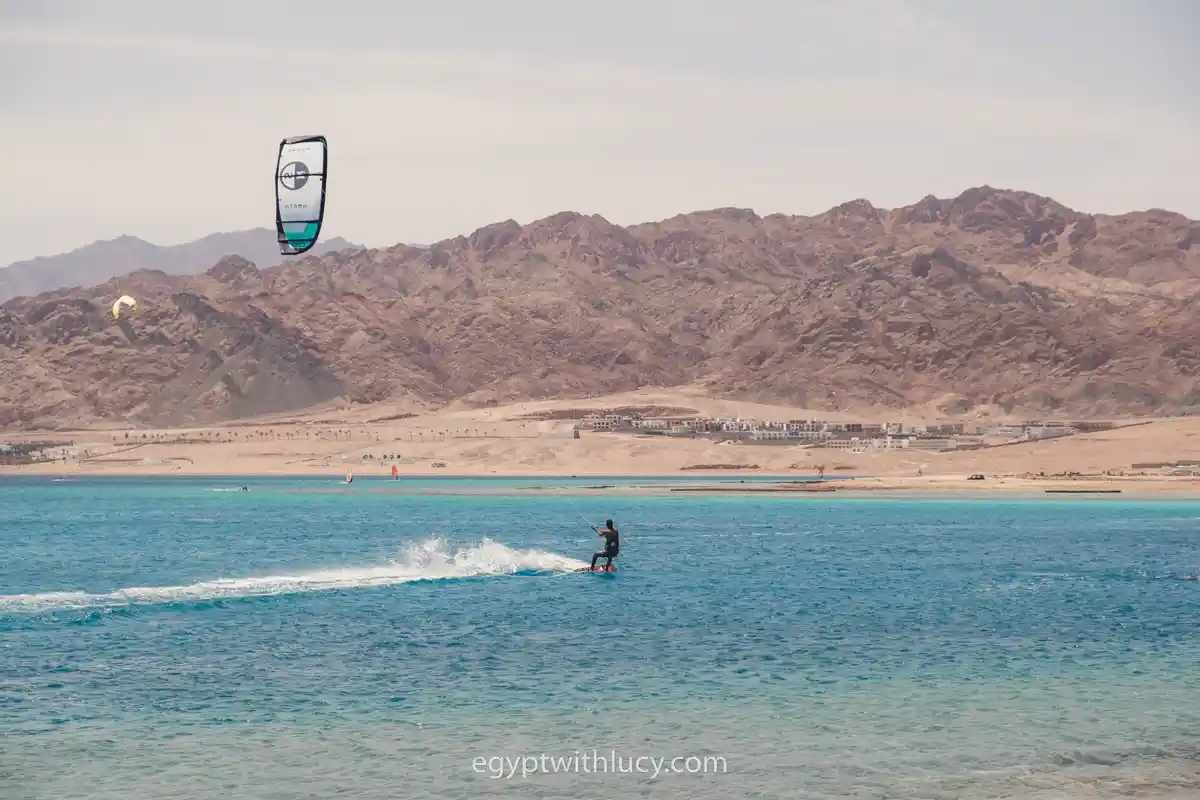 A kite surfer rides across the turquoise water near the shore at Laguna Beach.