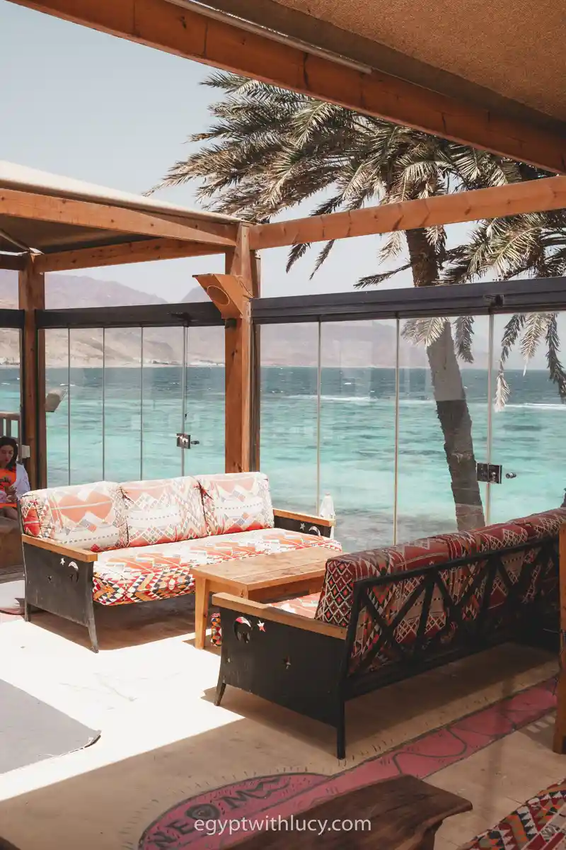 Patterned sofas and a wooden table sit by large glass windows overlooking the ocean at Neom's upstairs.