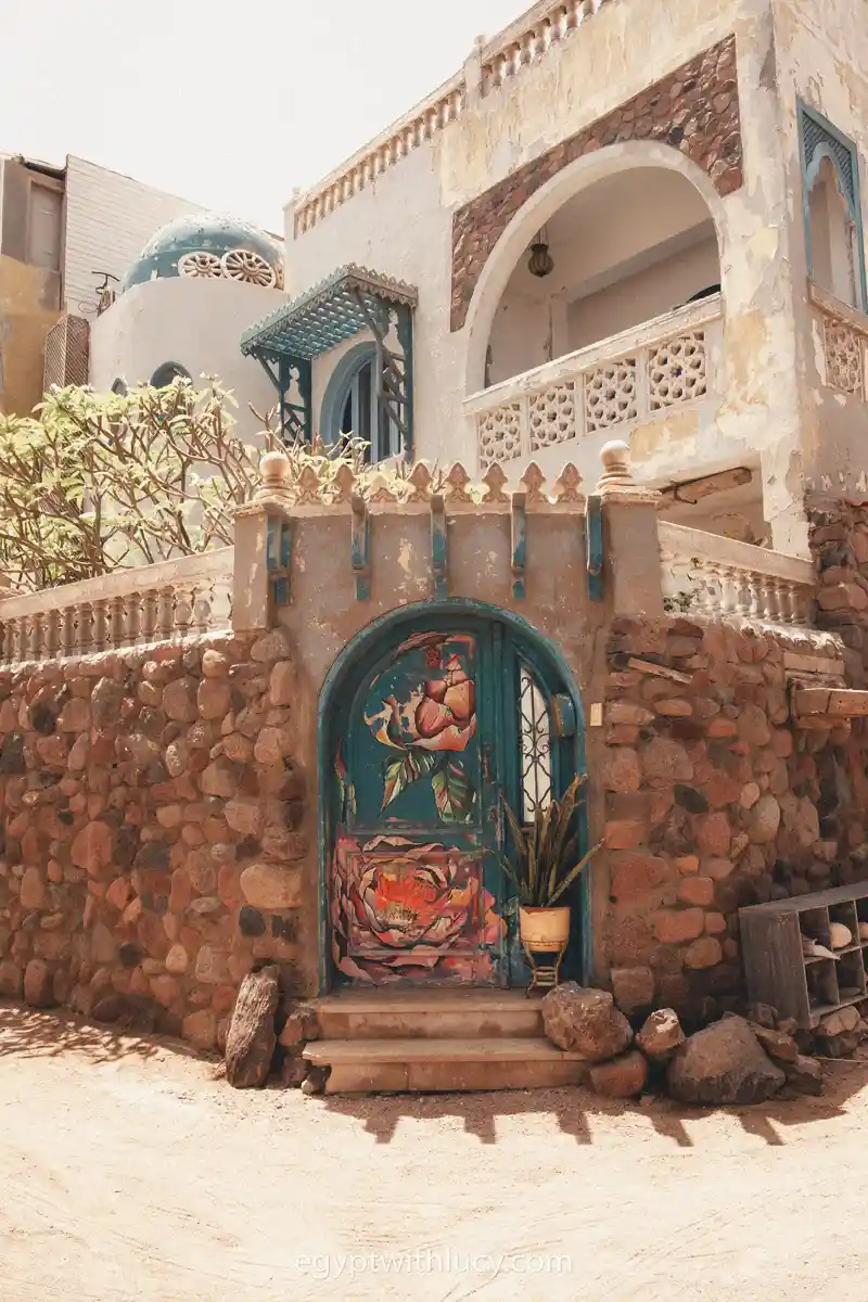 Painted arched wooden door set in a stone wall entrance of a building in Dahab.