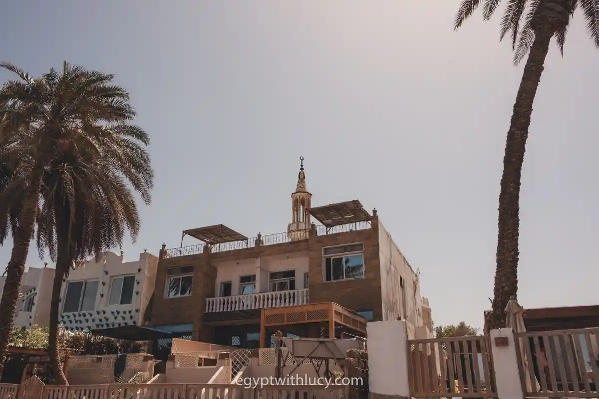 Multi-story building with palm trees under a clear sky in Dahab, Egypt.