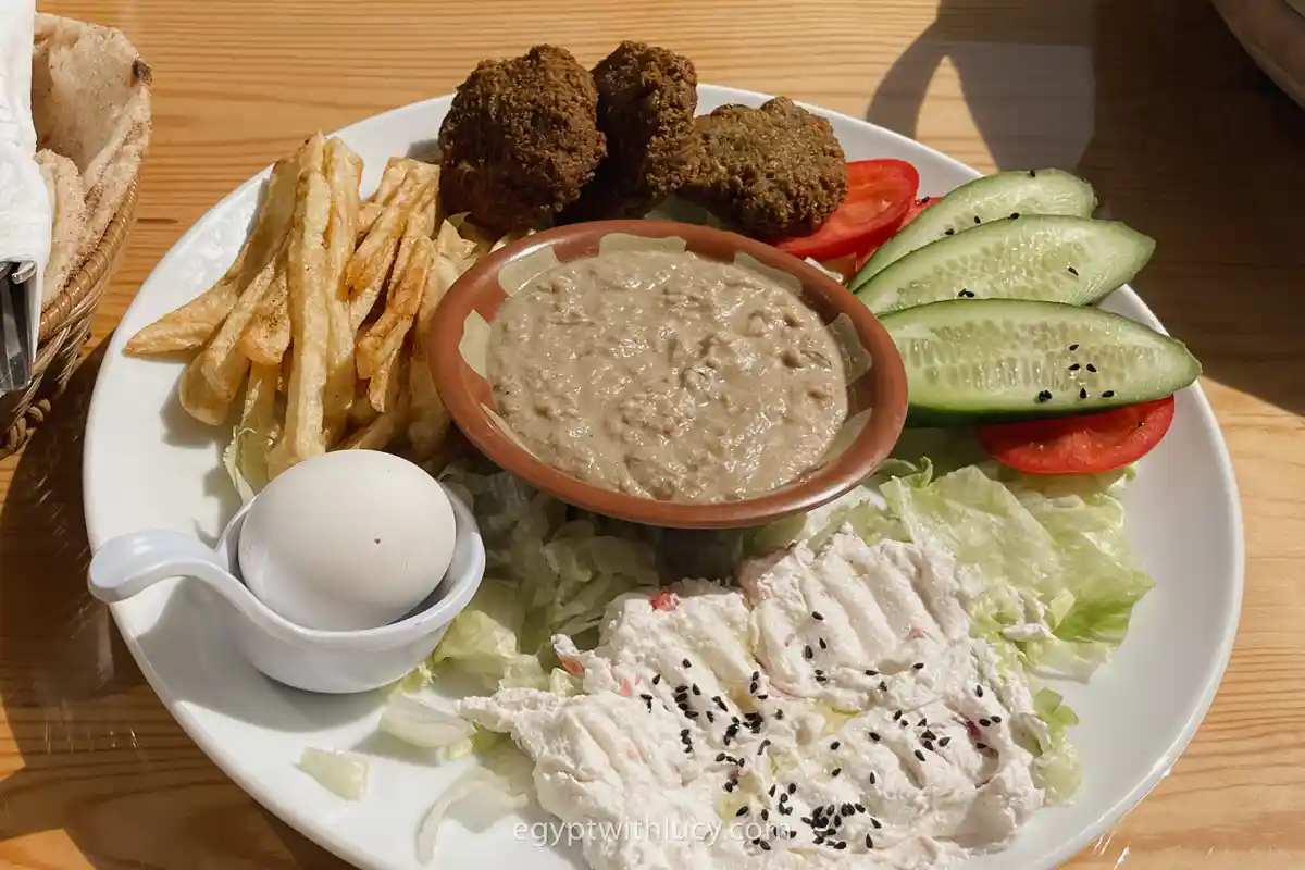 egyptian-foul-dish A platter featuring a bowl of foul surrounded by fries, egg, and falafel.