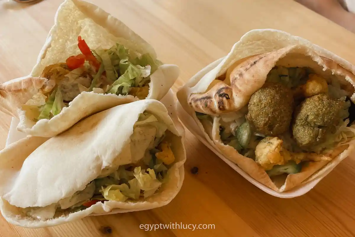 Three pita pockets filled with falafel patties, shredded lettuce, and chopped fresh vegetables.