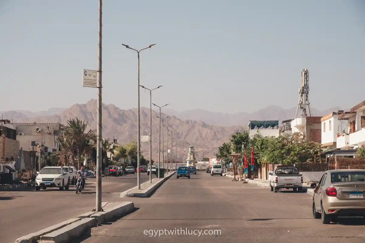 Wide asphalt road in Lighthouse with light posts leading toward distant desert mountains.